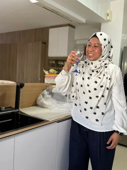 AquaLuxe customer holding a glass of water beside the EliteTap tap in their kitchen